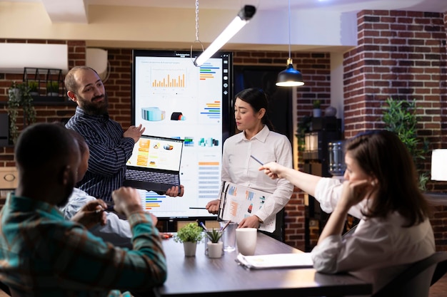 Team members presenting marketing data on a screen and laptop during a strategy meeting in a modern office.