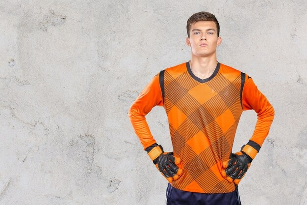 Unleash Your Team Spirit with Trendy Jerseys Online 3 Football player in red training uniform holding yellow ball against light background